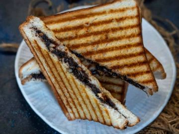 Grilled sandwich with chocolate spread on a white plate.