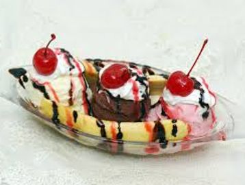 Banana split dessert with three scoops of ice cream and cherries.