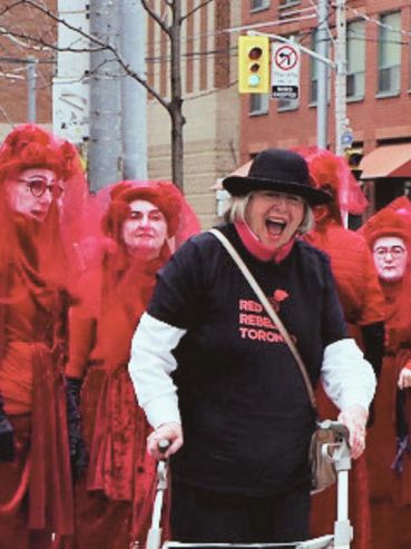 Group of people with one woman using a walker, dressed in red and black.