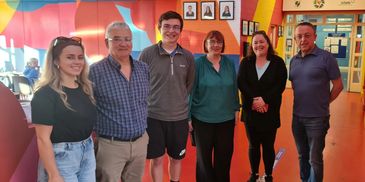 A group of six people smiling indoors.