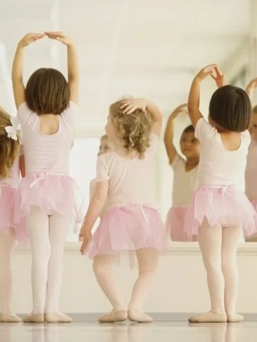 Young girls practicing ballet in pink tutus and white leotards.