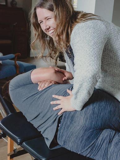 Dr. Kayla Rynne smiling while setting up a chiropractic adjustment on a patient 