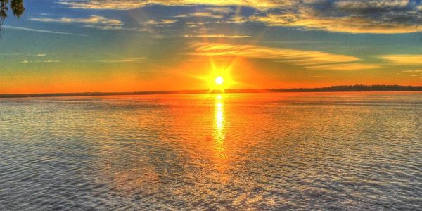 A vibrant sunset over a calm body of water with colorful clouds.
