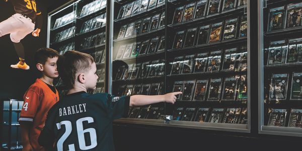 Two kids looking at sports cards in display cases.