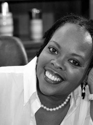 Smiling woman wearing a pearl necklace and white shirt.