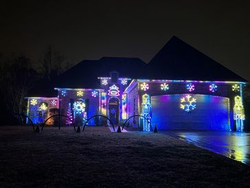 House decorated with colorful Christmas lights and nutcracker figures at night.