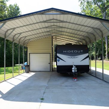 Covered parking with a Hideout camper and storage shed.