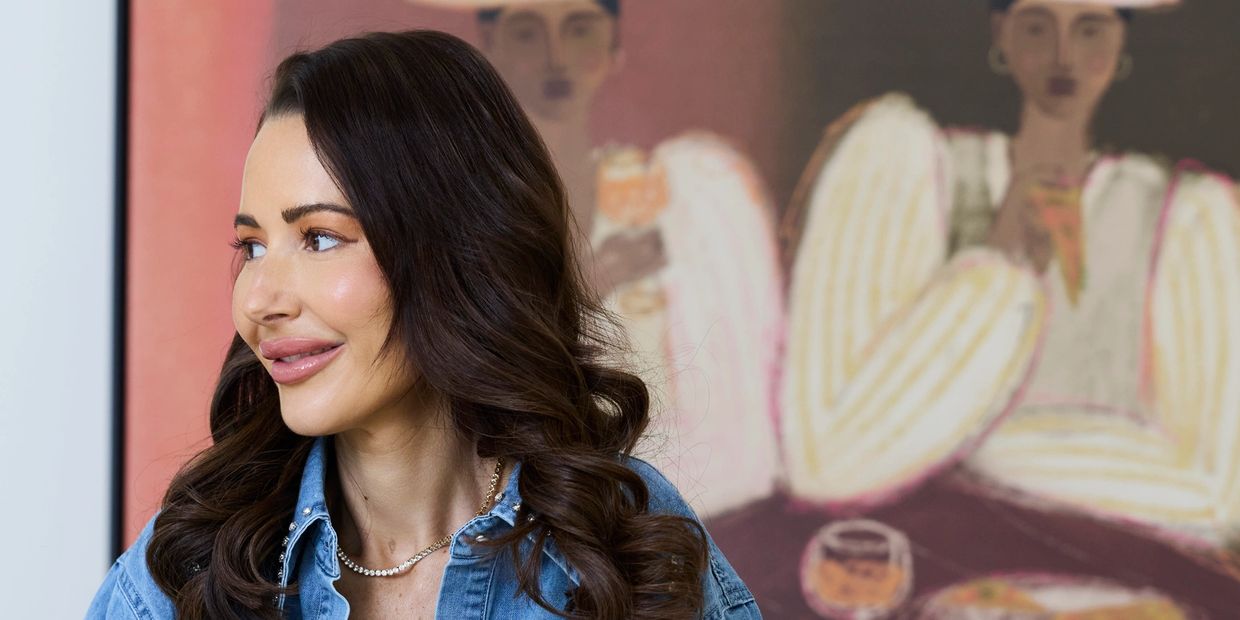 Smiling woman with long brown hair in a denim shirt portrait.