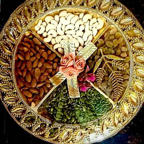 Decorative golden tray with assorted nuts and seeds, adorned with flowers.