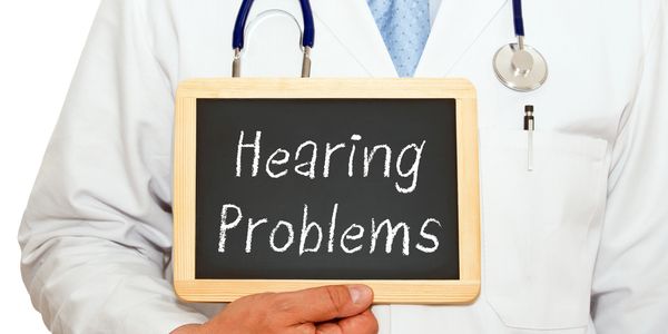 Doctor holding a sign that reads 'Hearing Problems'.