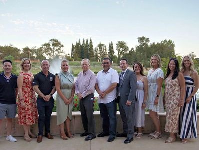 Group of people posing outdoors in business casual attire.