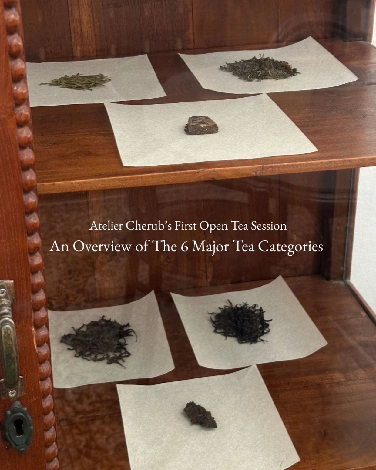 Display of six major tea categories on white papers in a wooden cabinet.