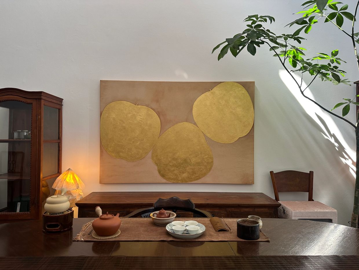 Cozy tea setup with golden art and indoor plant.