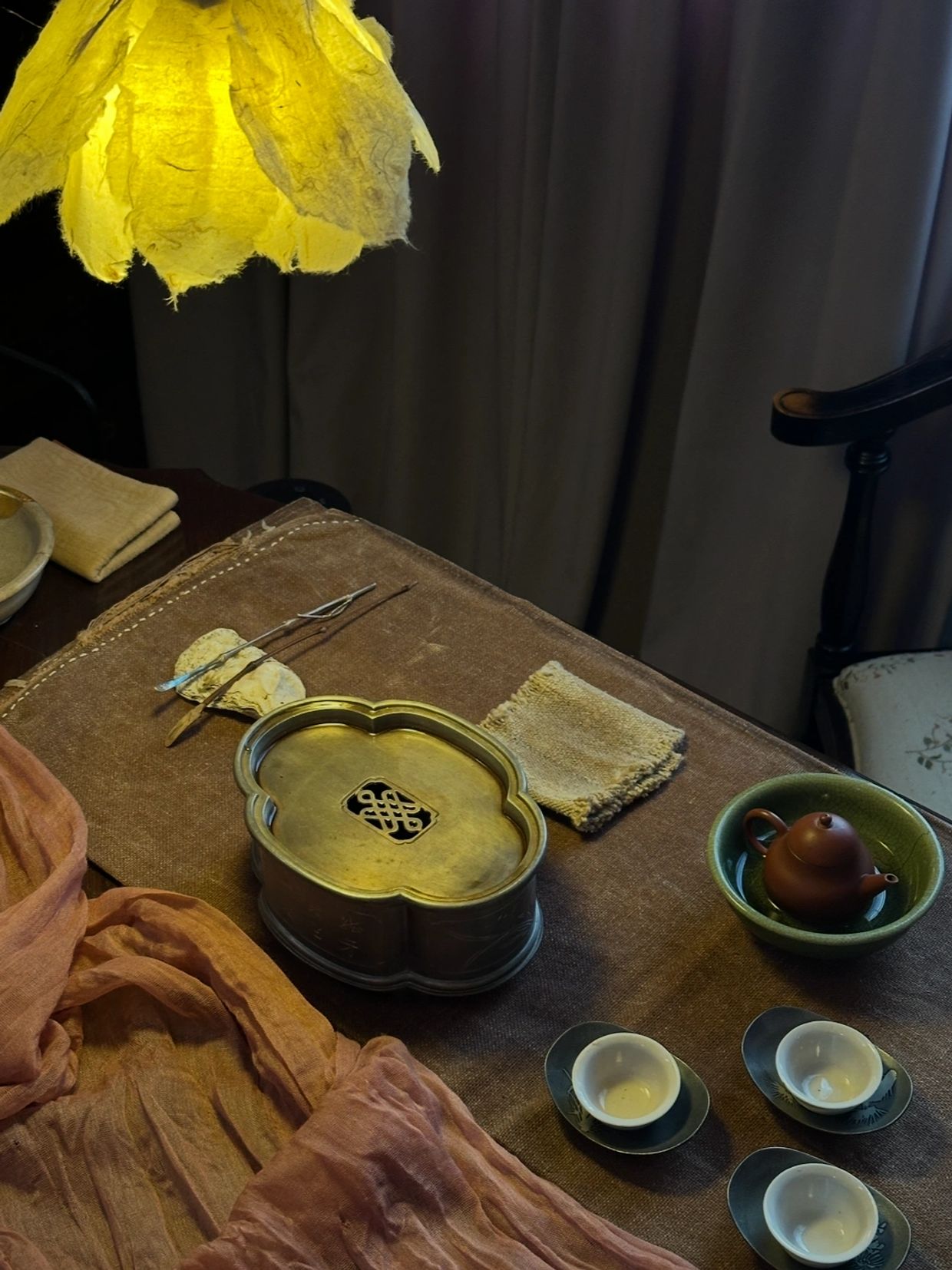 Cozy tea setup with traditional teapot, cups, and warm lighting.