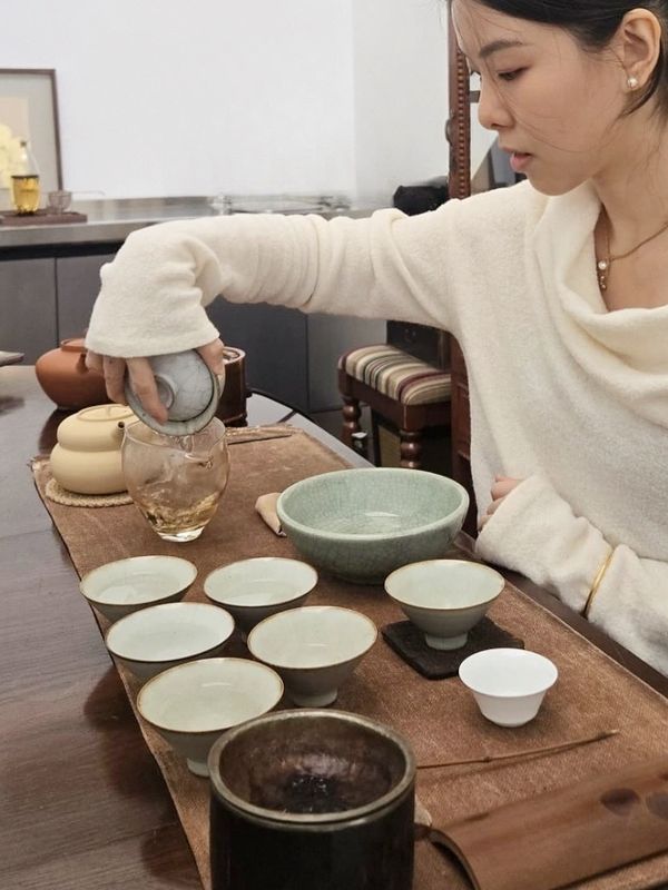 Woman pouring tea into a glass during tea ceremony.
