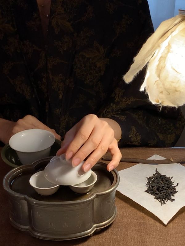 A person preparing tea using traditional Chinese tea set with loose tea leaves.