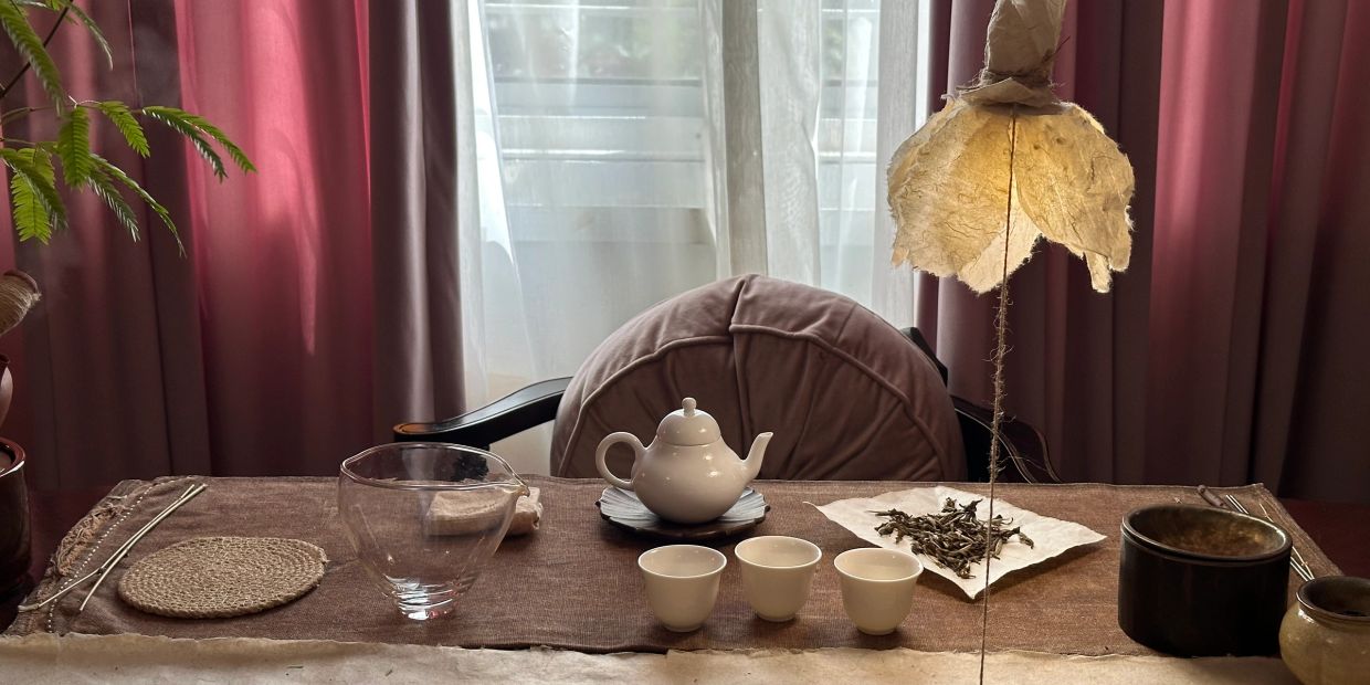 Serene tea setup with cups, teapot, and natural decor on a wooden table.