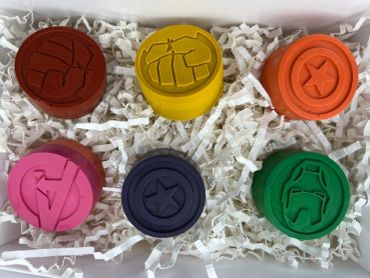 Six colorful superhero-themed wax seals in a box.