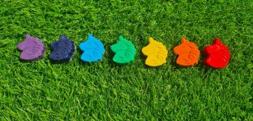 Colorful unicorn-shaped crayons on grass.
