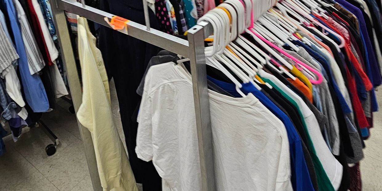 Clothes hanging on metal racks in a thrift store or closet.