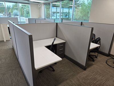 5x5 Friant cubicle installation with modern white desktops, gray fabric panels, and under-desk stora