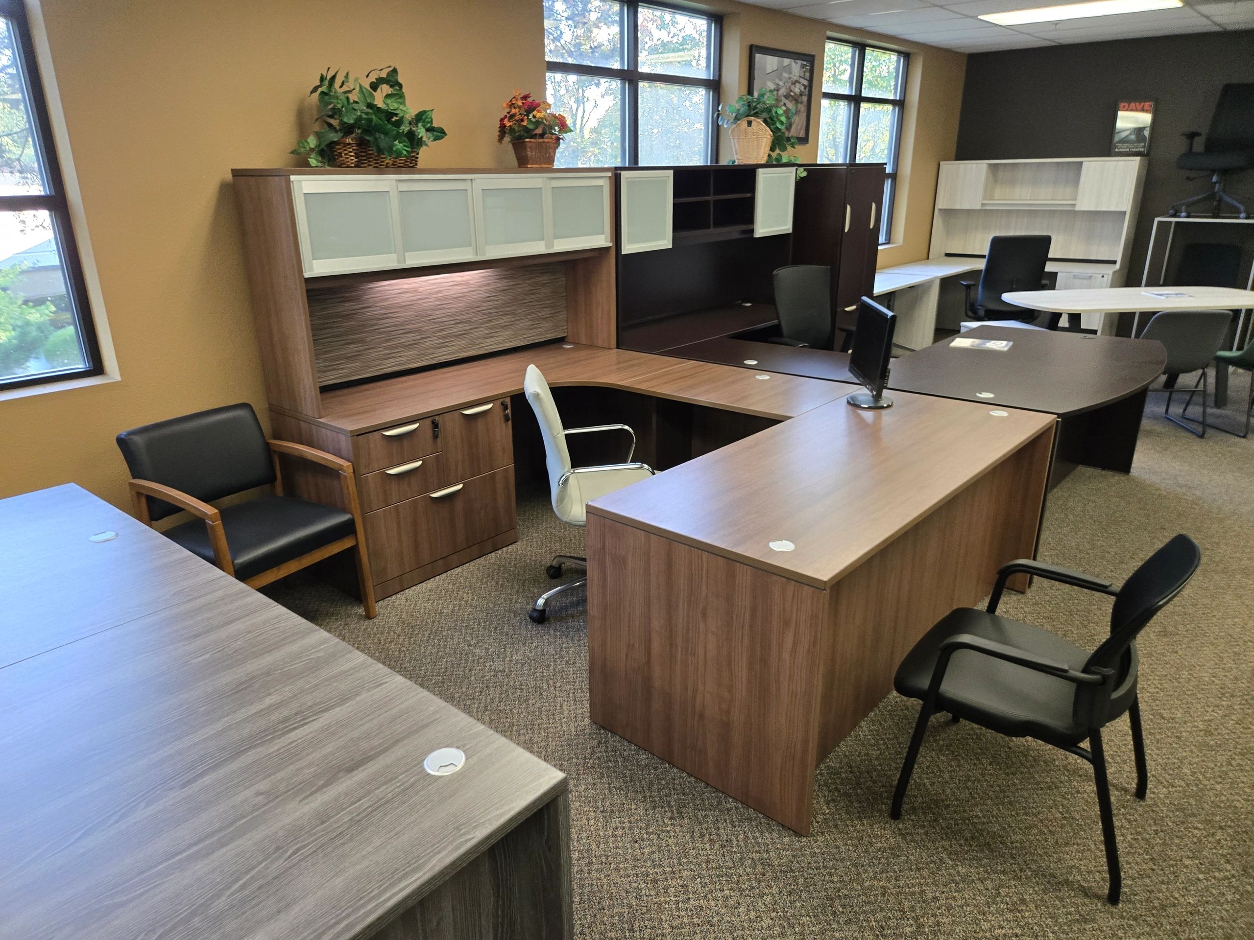 A professional office furniture showroom display featuring a modern U-shaped wooden desk with hutch 