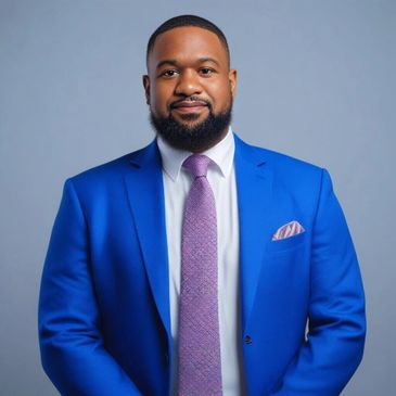 Confident man in a blue suit and purple tie posing against a gray background.