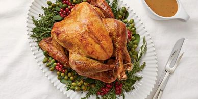 Turkey on platter with gravy boat and serving utensils.