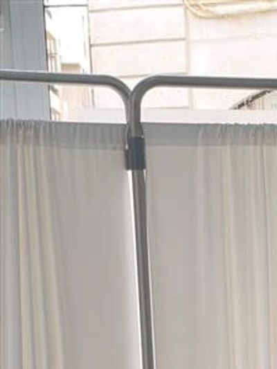 Metal frame with white curtains in a room near a window.