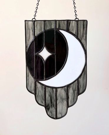 White moon with a white star and scalloped background in black glass