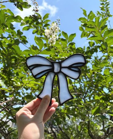 Stained glass blue ribbon in front of a green bush outside the artist home. 
