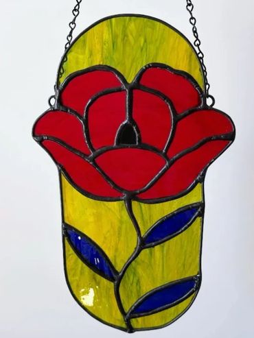Red poppy flower stained glass with blue leaves and bright green oval background.