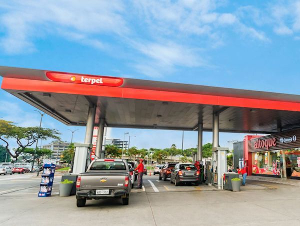 Gas station with cars refueling under a sunny sky.