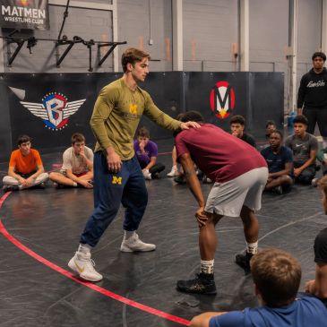 Wrestling coach demonstrates technique to students.