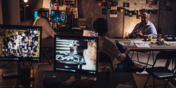 People working late in a dimly lit office with multiple computer screens.