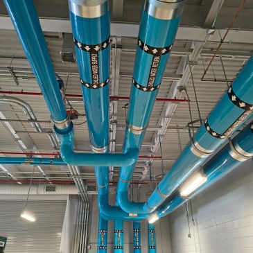 Blue ventilation ducts installed on a ceiling in an industrial setting.