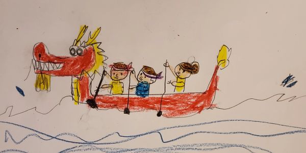 Children rowing a bright red dragon boat on blue waves.
