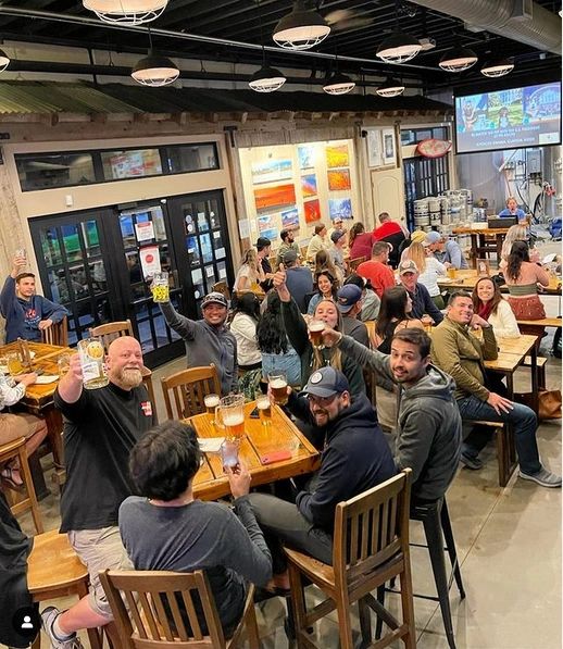 Group of friends enjoying drinks and raising glasses in a lively bar.