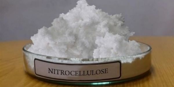 White nitrocellulose powder in a glass container.