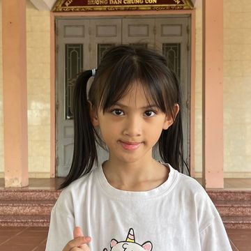 Young girl with pigtails standing indoors.