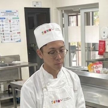Chef wearing white uniform and hat in a kitchen.