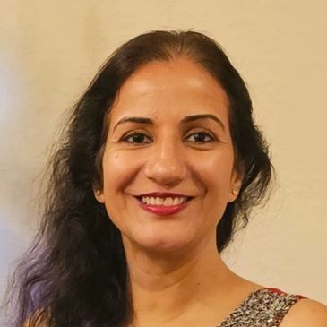 Portrait of a smiling woman with long dark hair and a patterned top.