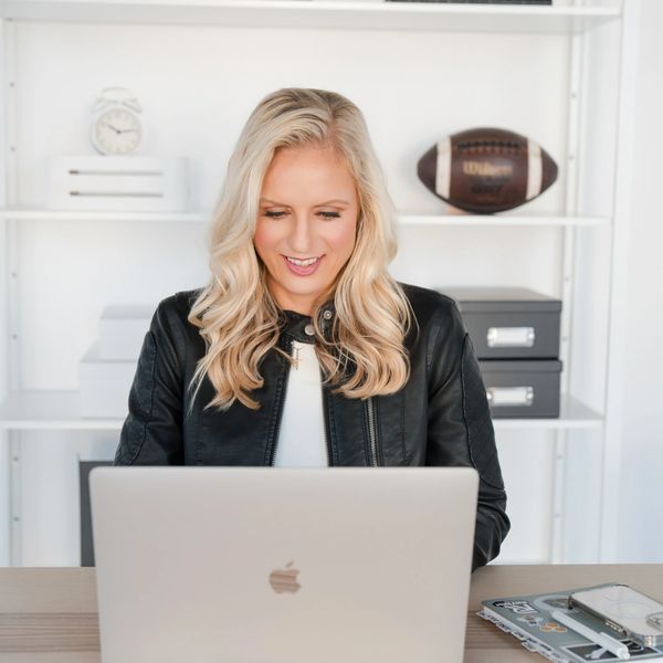 Blonde woman working on laptop, smiling.