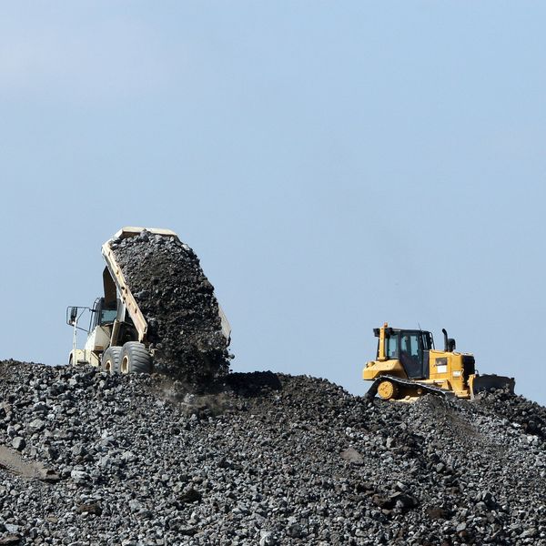 Dump truck unloading coal while bulldozer works on a coal pile.