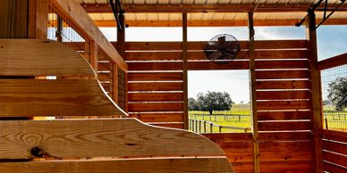 Interior view of a wooden barn with an open door showing a green field outside.