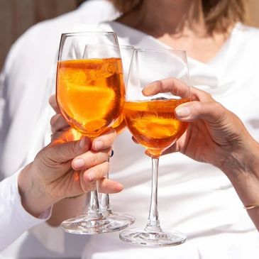 Three people clinking glasses filled with an orange drink and ice cubes.
