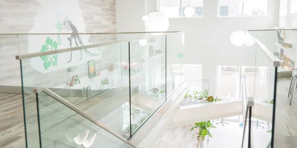 Modern staircase with glass railings and spherical hanging lights in a bright space.