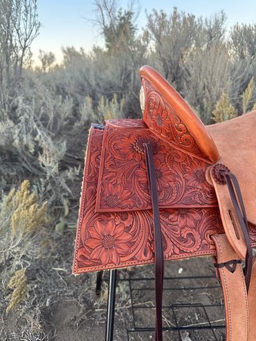 Leather saddle with intricate floral carvings.