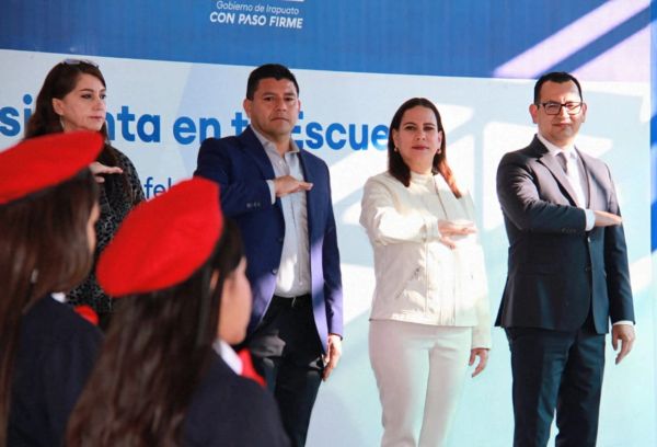 Four adults standing with arms raised, facing children in red berets.