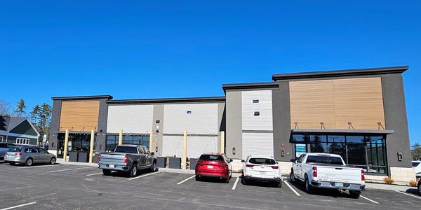 Modern commercial building with parking lot and several vehicles.